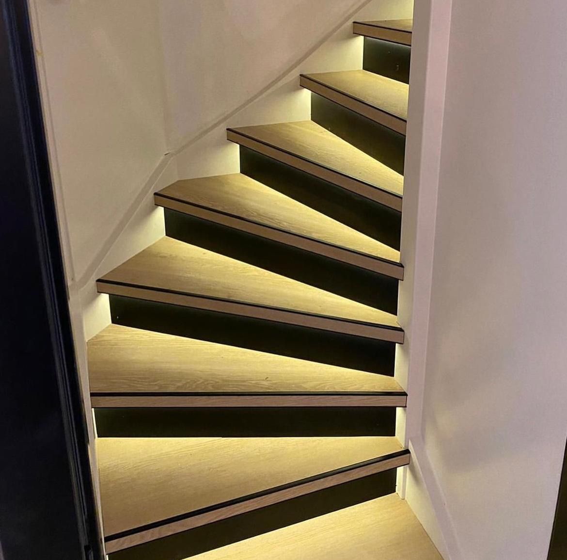 Trap met eiken treden en zwarte stootborden, met ingebouwde LED-strips onder elke trede