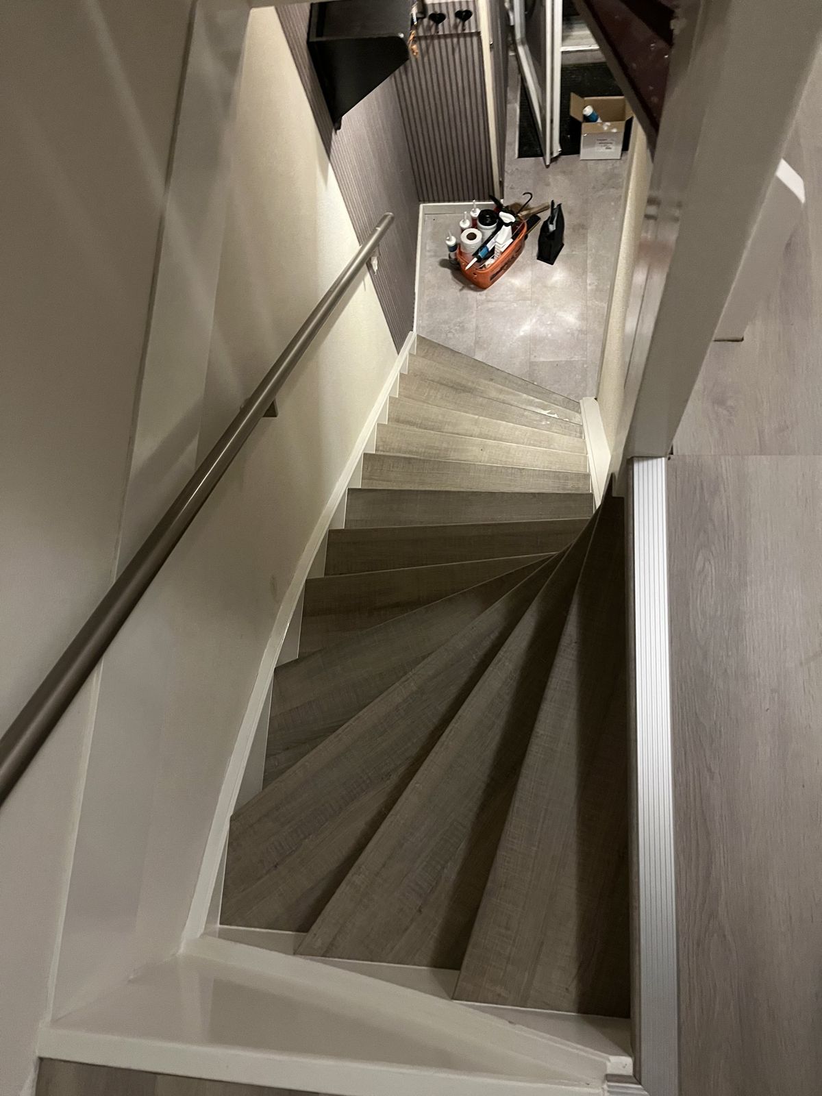 Gedraaide trap in grijze houtlook met rvs leuning, van bovenaf