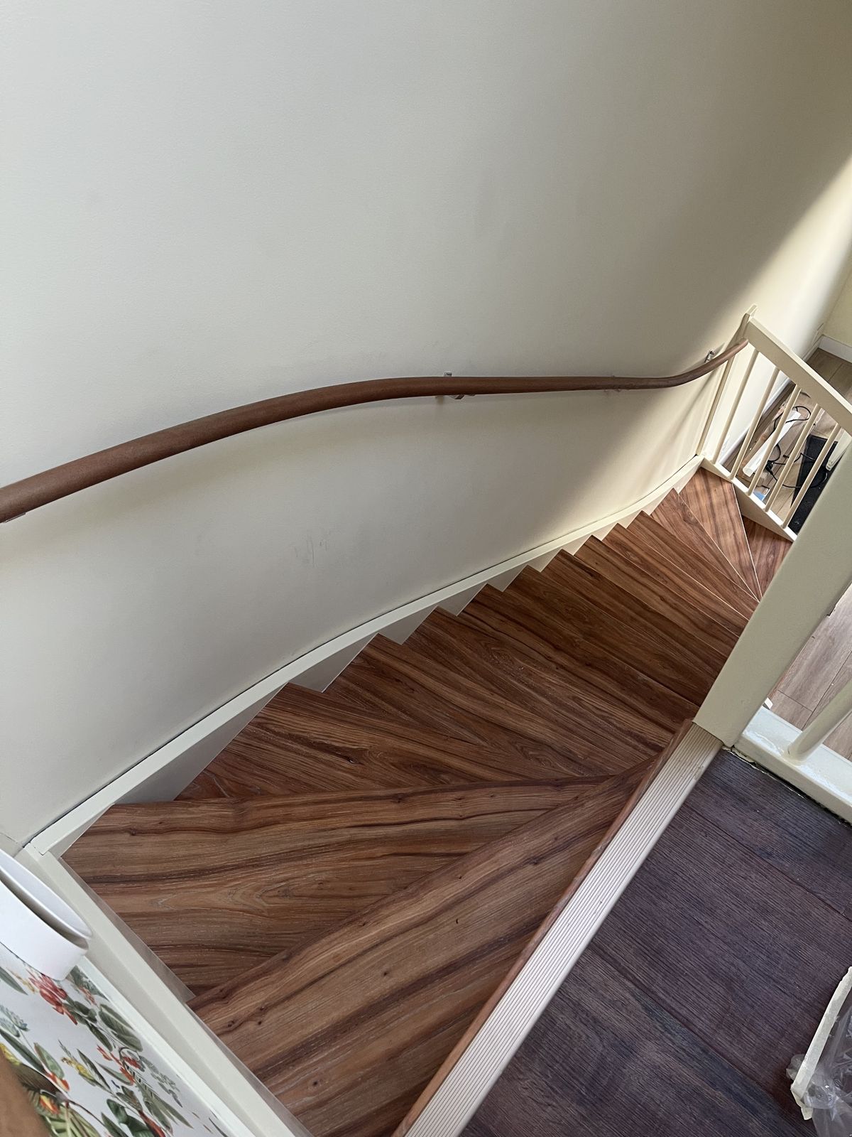 Gedraaide trap in warme houtlook met witte balustrade en houten leuning